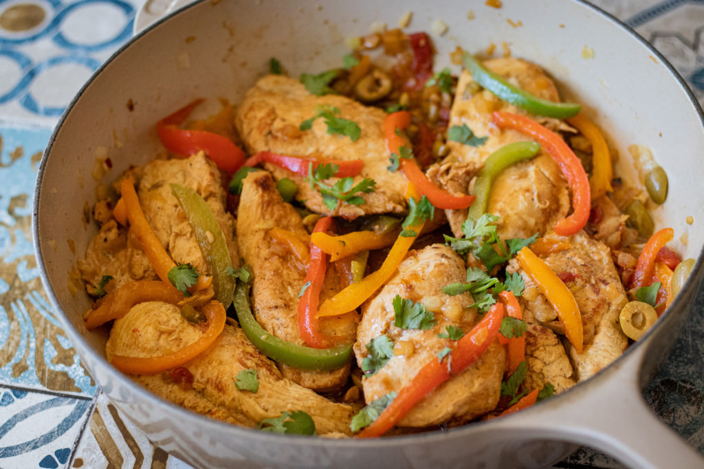 Pan Seared Chicken in a deep skillet with onions, peppers and olives around it