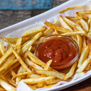 french fries in a serving platter with a small bowl of ketchup in the center of the platter
