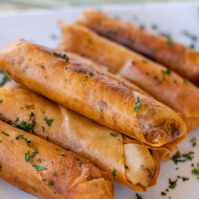 a stack of spring rolls with chopped parsley over top