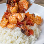 shrimp and bacon stew being served over white rice on a plate
