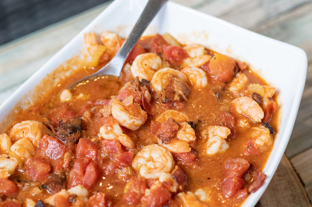 large serving platter with shrimp and bacon in a tomato stew