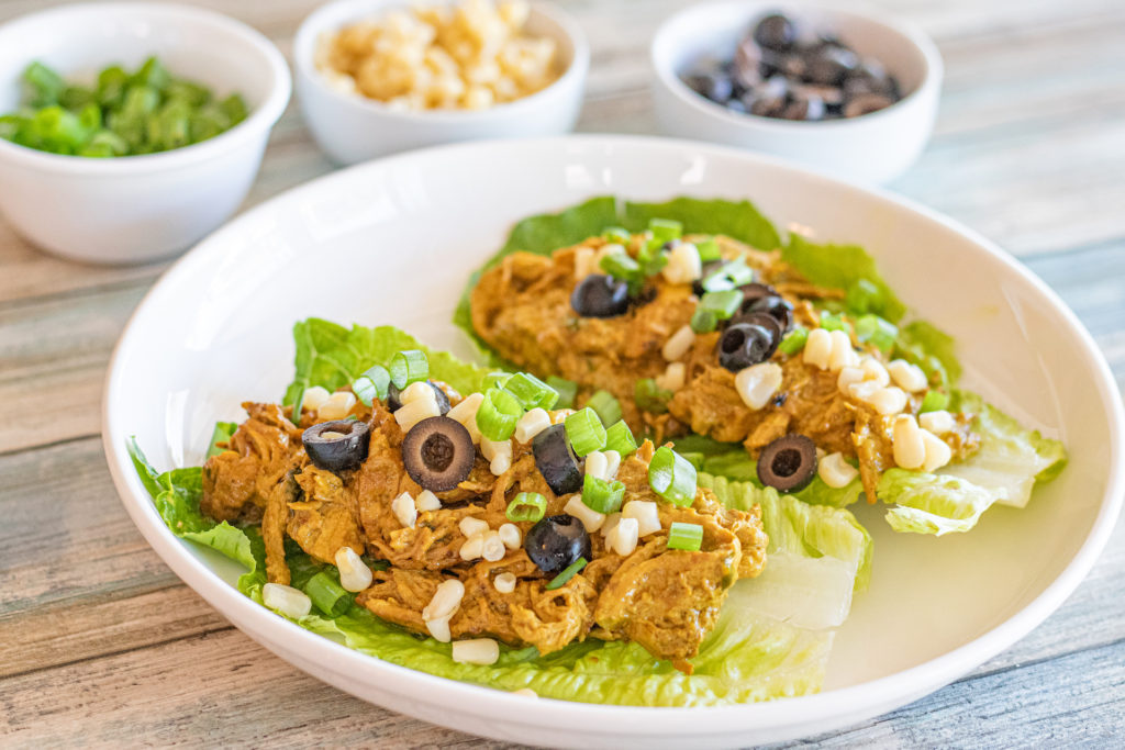 shredded chicken on lettuce cups topped with chopped olives, corn and green onions