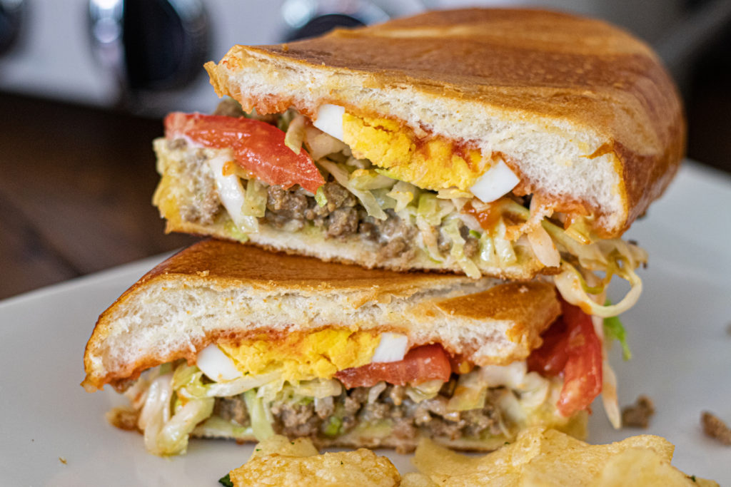 a dominican riki taki pressed sandwich. It has ground beef, shredded cabbage, boiled eggs, tomato, ketchup and mayo.