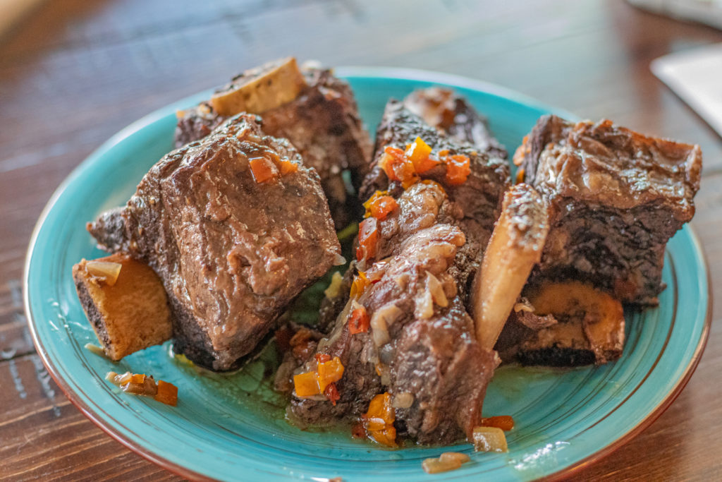 Several pieces of Latin style braised short ribs on a small plate.