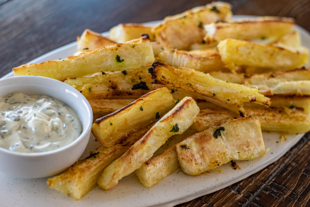 close up of a serving platter of baked yucca fries with mayo dipping sauce on the side