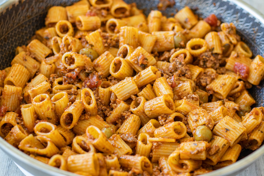 Beef Picadillo Ragu sitting in the pan it was cooked in. This dish is made with mezze rigatoni which is the smaller size rigatoni.