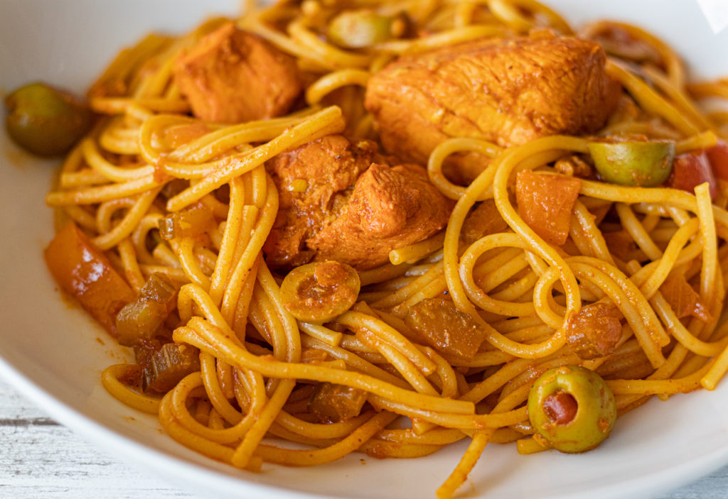 a plate of panamanian stewed chicken with spaghetti.
