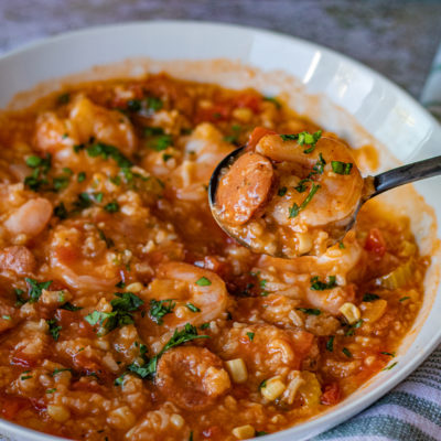 a bowl of Instant Pot Jambalaya Soup with a spoon holding some of the shrimp and sausage. It's a hearty and thick soup.
