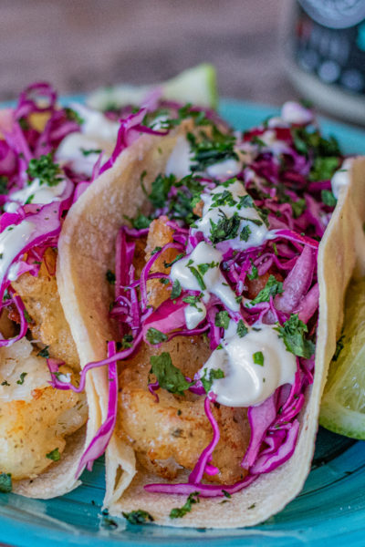 Cod Fish Tacos with Red Cabbage Slaw and Mayo Aioli over top in a corn tortilla.