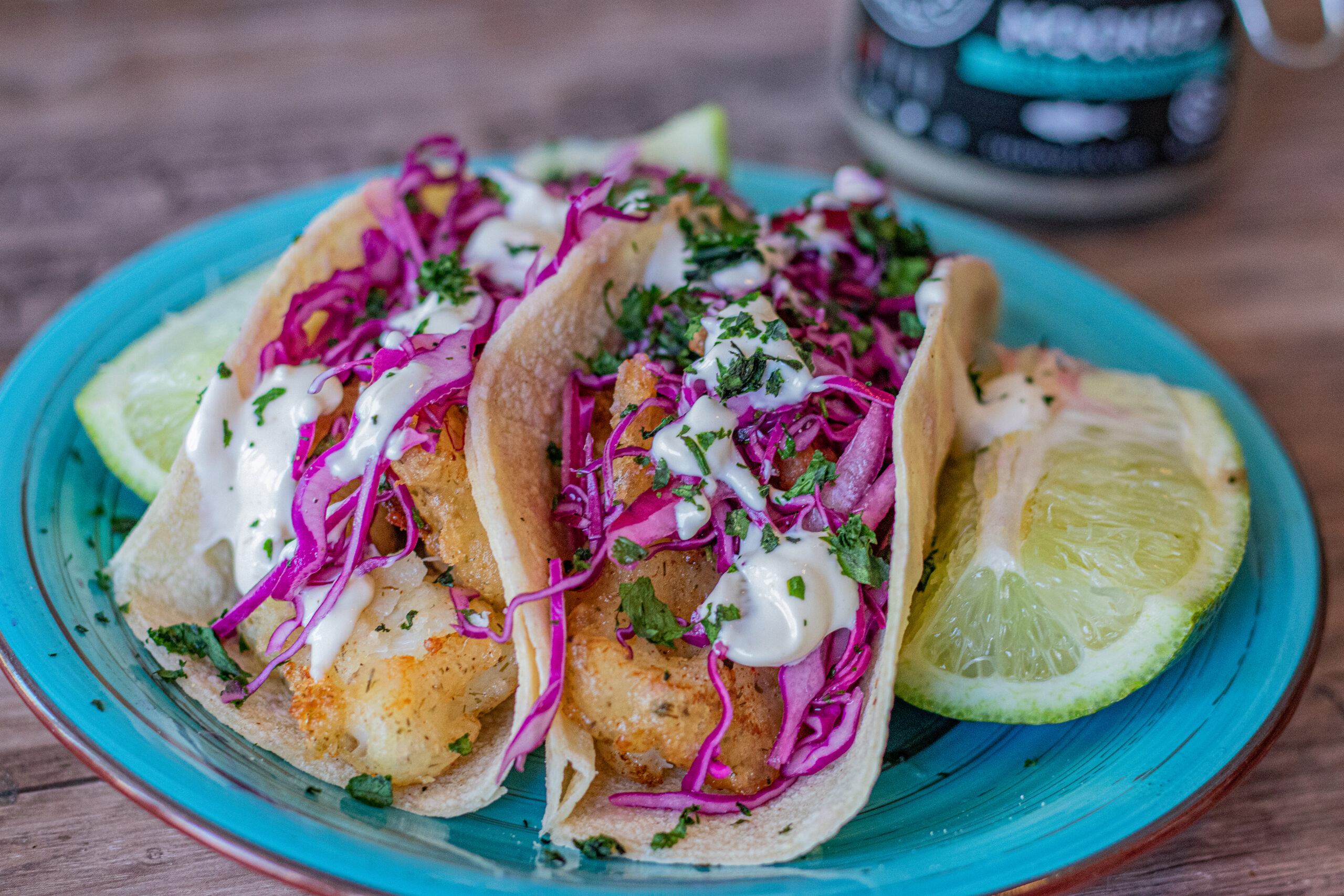 Cod Fish Tacos with Red Cabbage Slaw and Mayo Aioli over top in a corn tortilla.