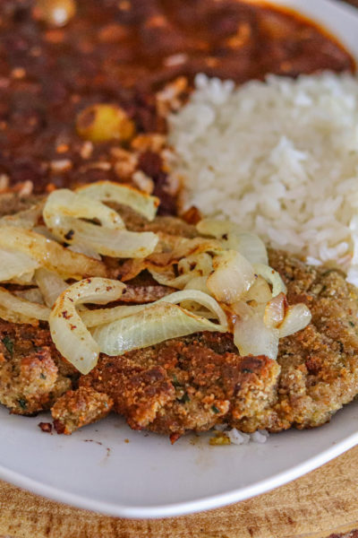 Cuban Bistec Encebollado on a plate with white rice and beans.