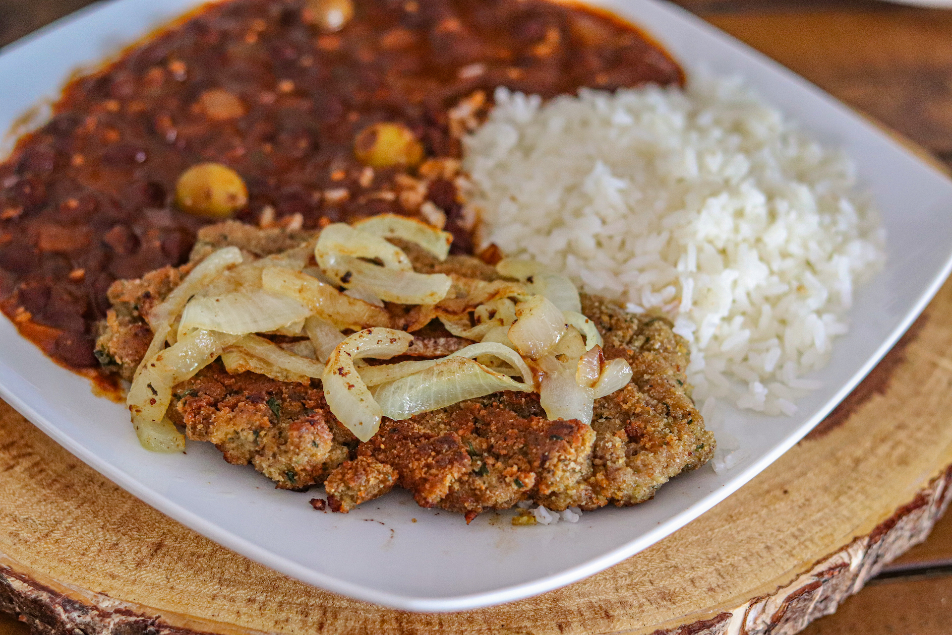 Cuban Bistec Encebollado on a plate with white rice and beans.