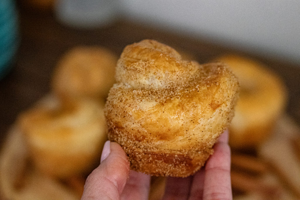 Easy Churro Popovers. One is being held up by a hand for a super close up of it.