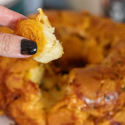 Spicy Chorizo Monkey Bread with a hand holding a piece of it in fron fron of the camera.
