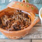 Cooked Beef Birria sitting in a Mexican style clay small serving dish.