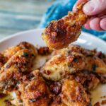 Chicken Marsala Wings with Pancetta. A hand is holding a drumstick up. You can see the bits of pancetta over the wings as well. Delicious!
