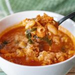 Pasta al Fagioli Soup with a Latin Twist in a single serving bowl. Already topped with grated parmesan with a spoonful about to be enjoyed and close up to the camera.