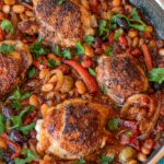 Mexican Chicken in Bravas Sauce in the skillet cooked in. Made of chicken thighs, onions, peppers, diced tomatoes, olives and white beans.