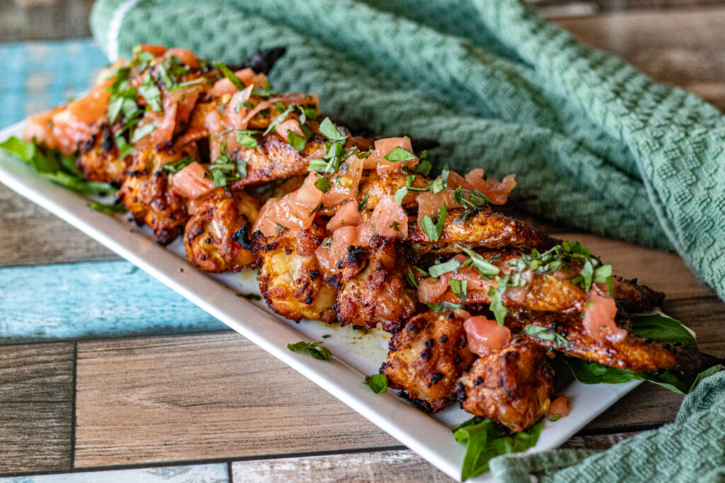 Chicken Wings with Tomato Dressing. A Spanish Tapas dish. You can see bits of tomato and basil over the wings.