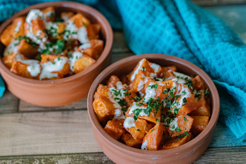Easy Spanish Patatas Bravas with Aioli in two small individual serving bowls.